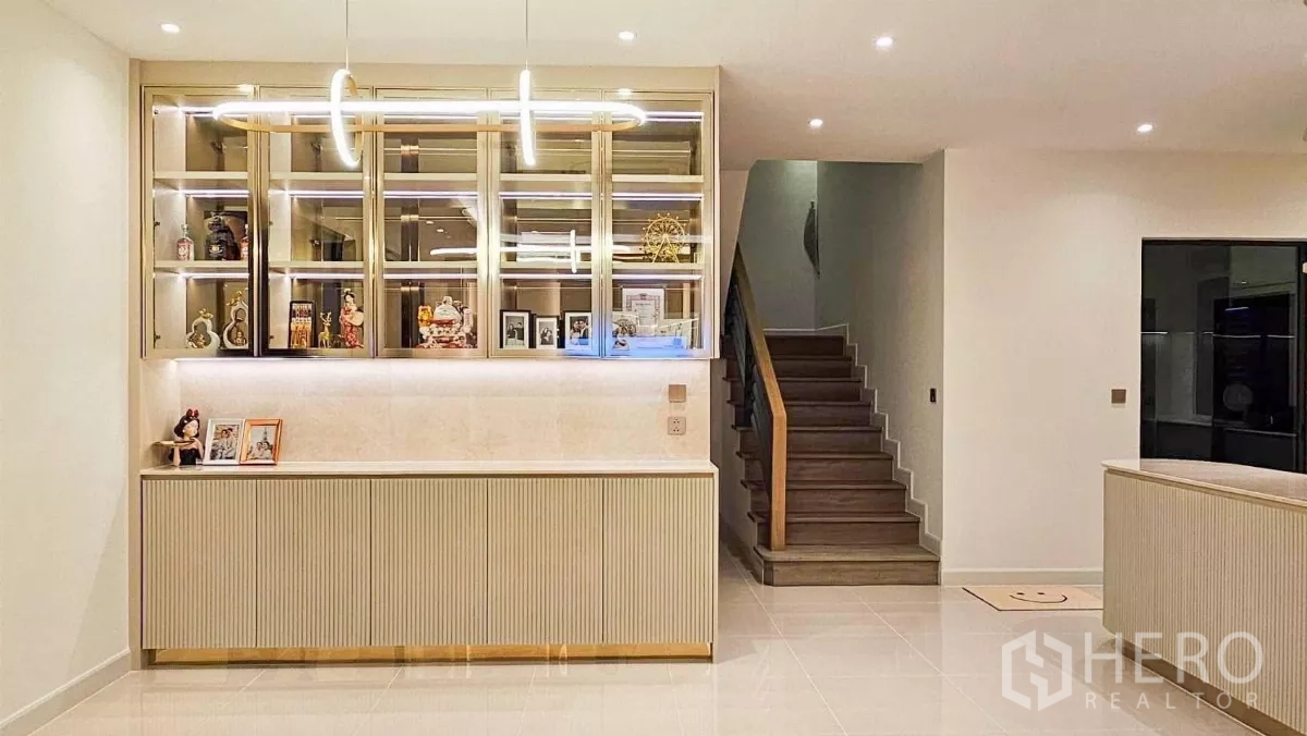Detached House for rent or sale in Prawet, Bangkok - Entry hallway with illuminated display cabinet, pendant light and wooden staircase to the upper floor.