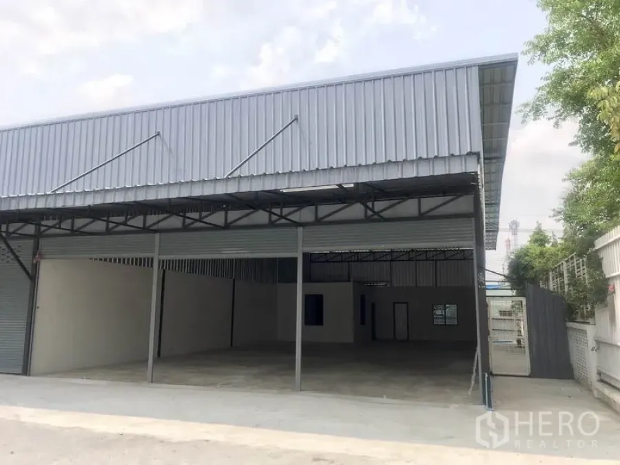 Warehouse for rent in Pathum Thani - Modern metal-clad warehouse frontage with roller shutters and sheltered loading area.