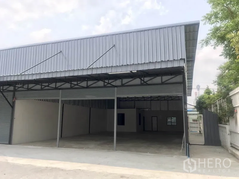 Warehouse for rent in Pathum Thani - Modern metal-clad warehouse frontage with roller shutters and sheltered loading area.