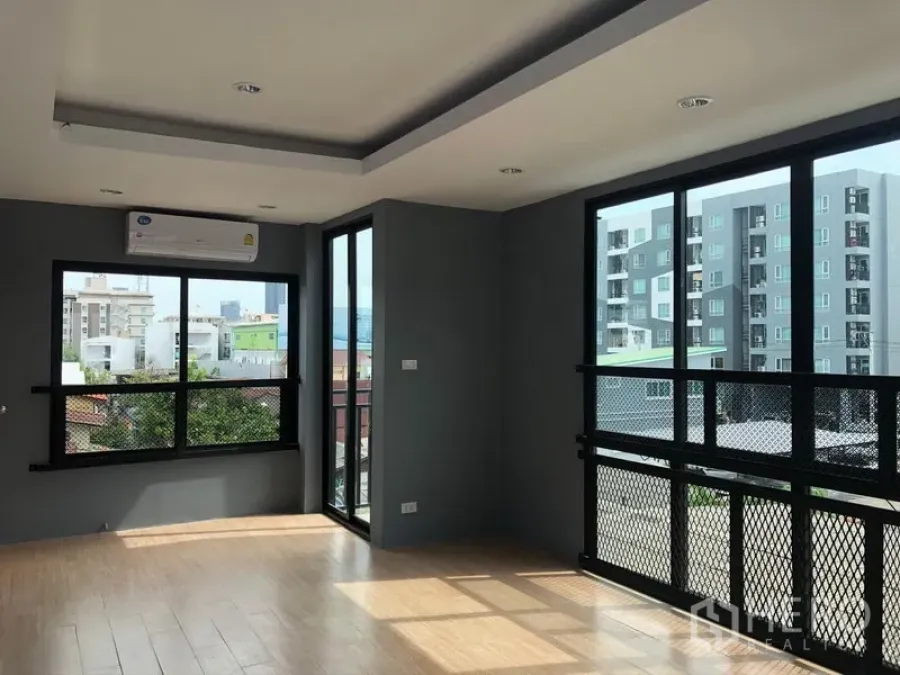 Home Office for rent in Suan Luang, Bangkok - Bright corner office with floor-to-ceiling windows and wood-look floors overlooking city buildings.