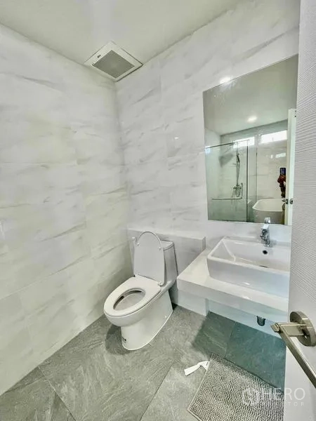 Townhouse for rent or sale in Prawet, Bangkok - Clean bathroom with marble‑effect walls, vanity and a glass shower area.