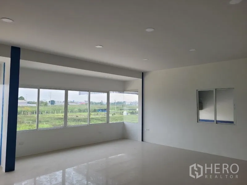 Factory for rent or sale in Khlong Luang, Pathum Thani - Spacious corner office with wraparound windows and glossy floor finish.