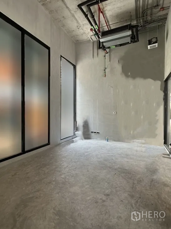 Retail Space for rent in Khlong Toei, Bangkok - Unfurnished retail unit with concrete floor, frosted glass panels, and exposed ceiling ducts.