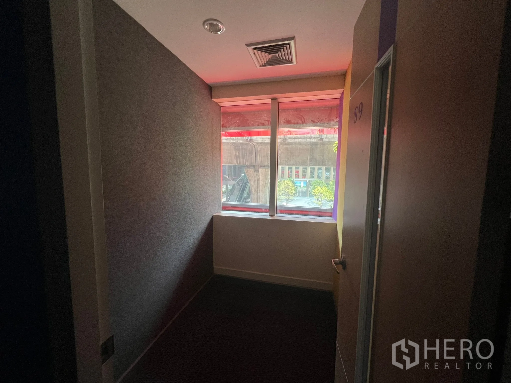 Retail Space for rent - Small office room with window, carpet and red window frame bringing in daylight.