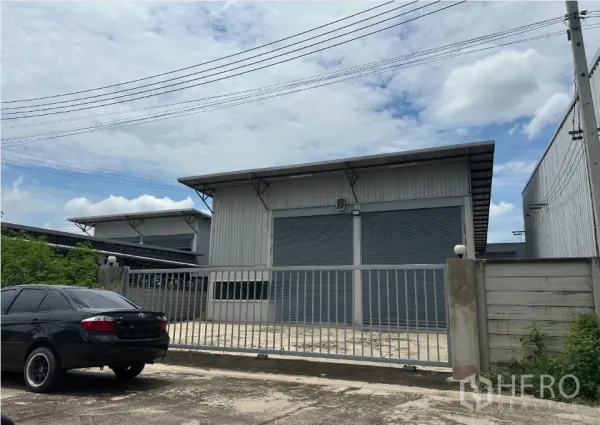 货栈 出售在Bang Len, Nakhon Pathom - 工业仓库外观，灰色卷闸门与围栏，前方有停车装卸区。