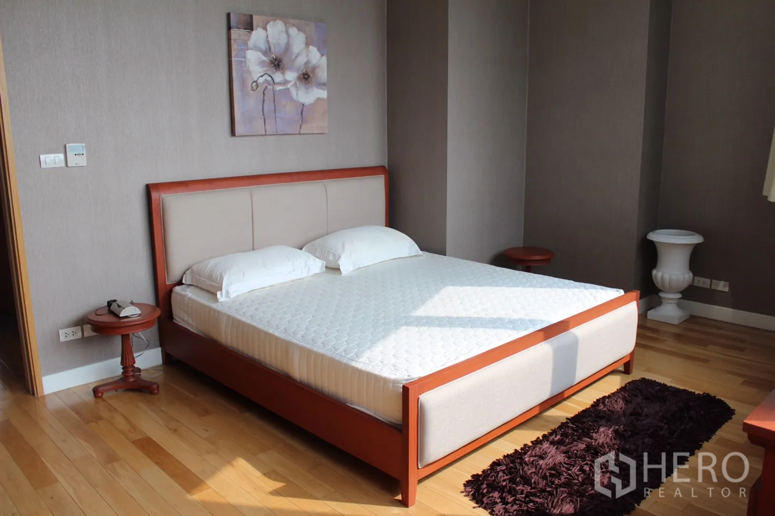 Condominium for rent in Khlong Toei, Bangkok - Master bedroom with wood-framed bed, neutral walls, hardwood flooring and natural light.