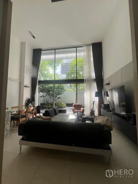 Townhouse for rent - Cozy living room with large windows, dining set and TV wall