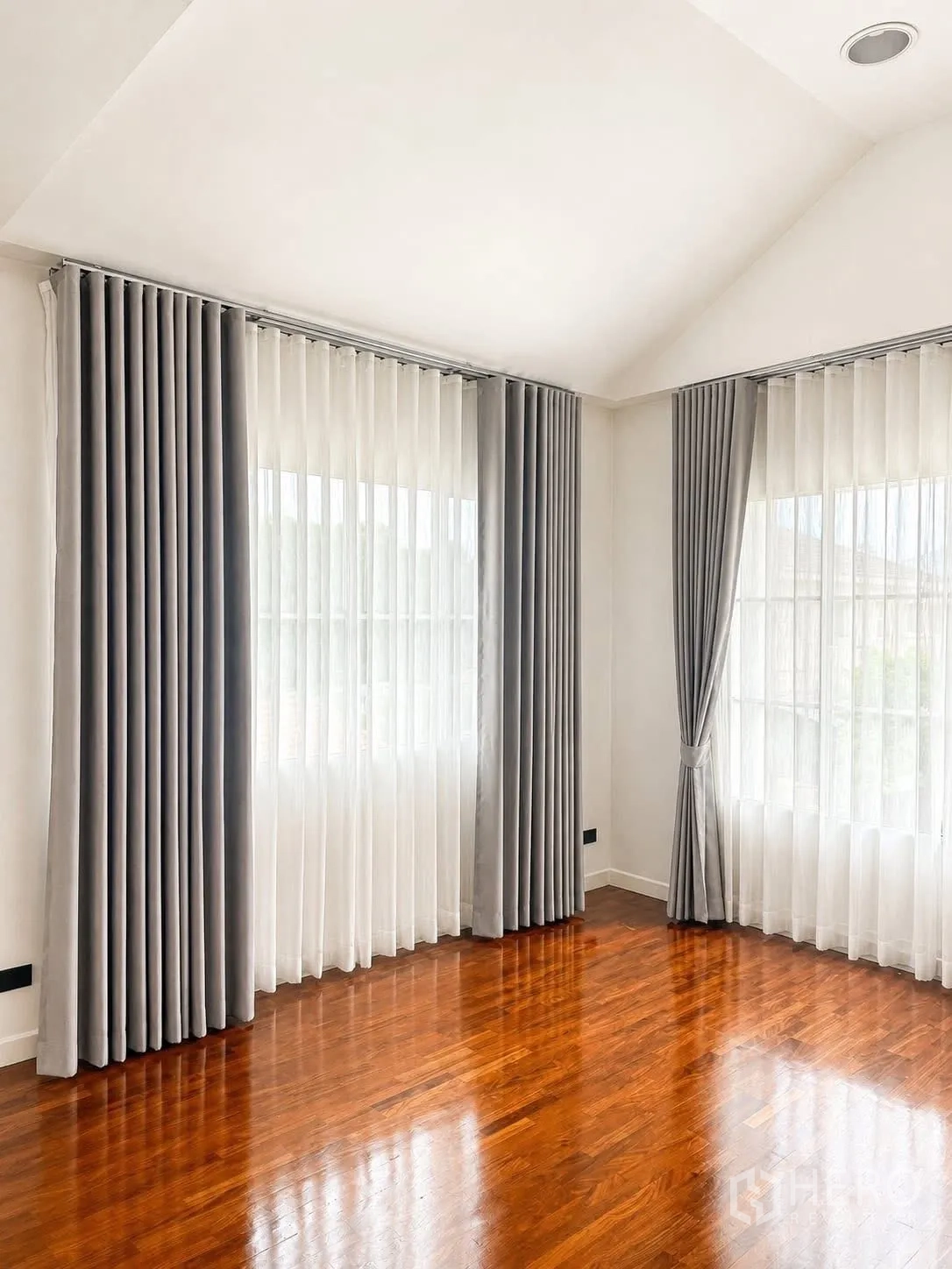 Detached House for rent in Prawet, Bangkok - Sunlit empty room with corner windows, sheer and blackout curtains, and wood floors.