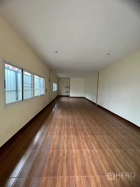 Warehouse for rent in Lat Krabang, Bangkok - Long office space with wood‑look tile flooring, windows along one wall, and recessed lighting.