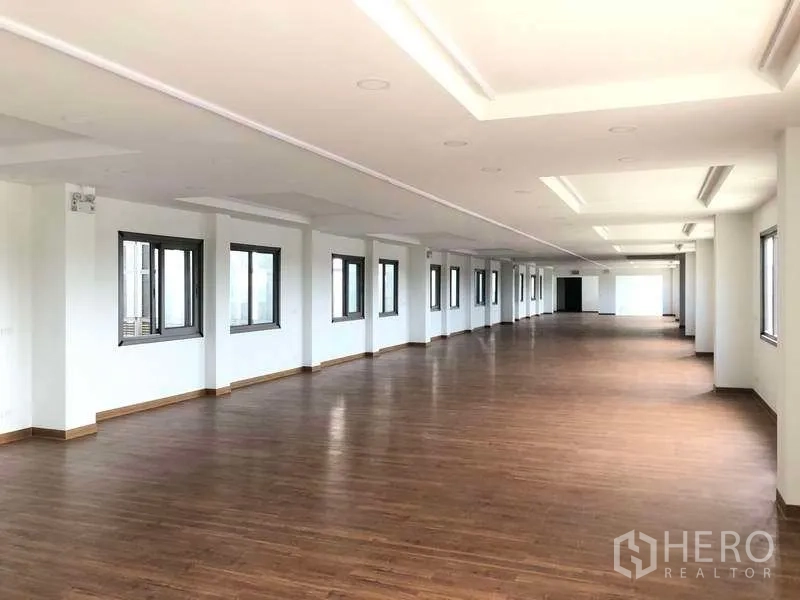 Factory for rent or sale in Samut Prakan - Long open-plan office floor with recessed lighting and multiple windows.