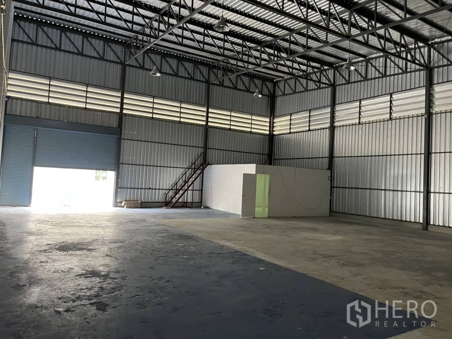 Warehouse for rent in Bang Phli, Samut Prakan - Spacious storage hall showing an internal office unit and staircase beside the shutter door.