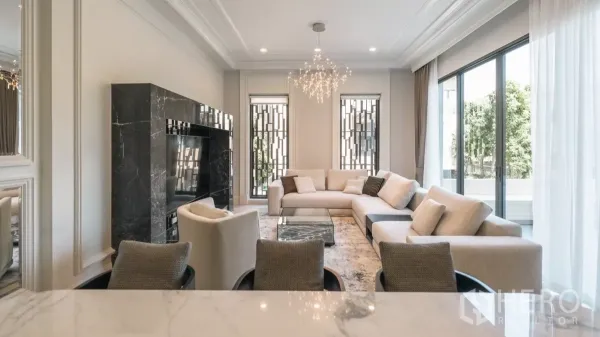 Detached House for rent or sale in Bang Kapi, Bangkok - Bright lounge with L-shaped sofa, glass doors to a terrace and a marble feature wall.