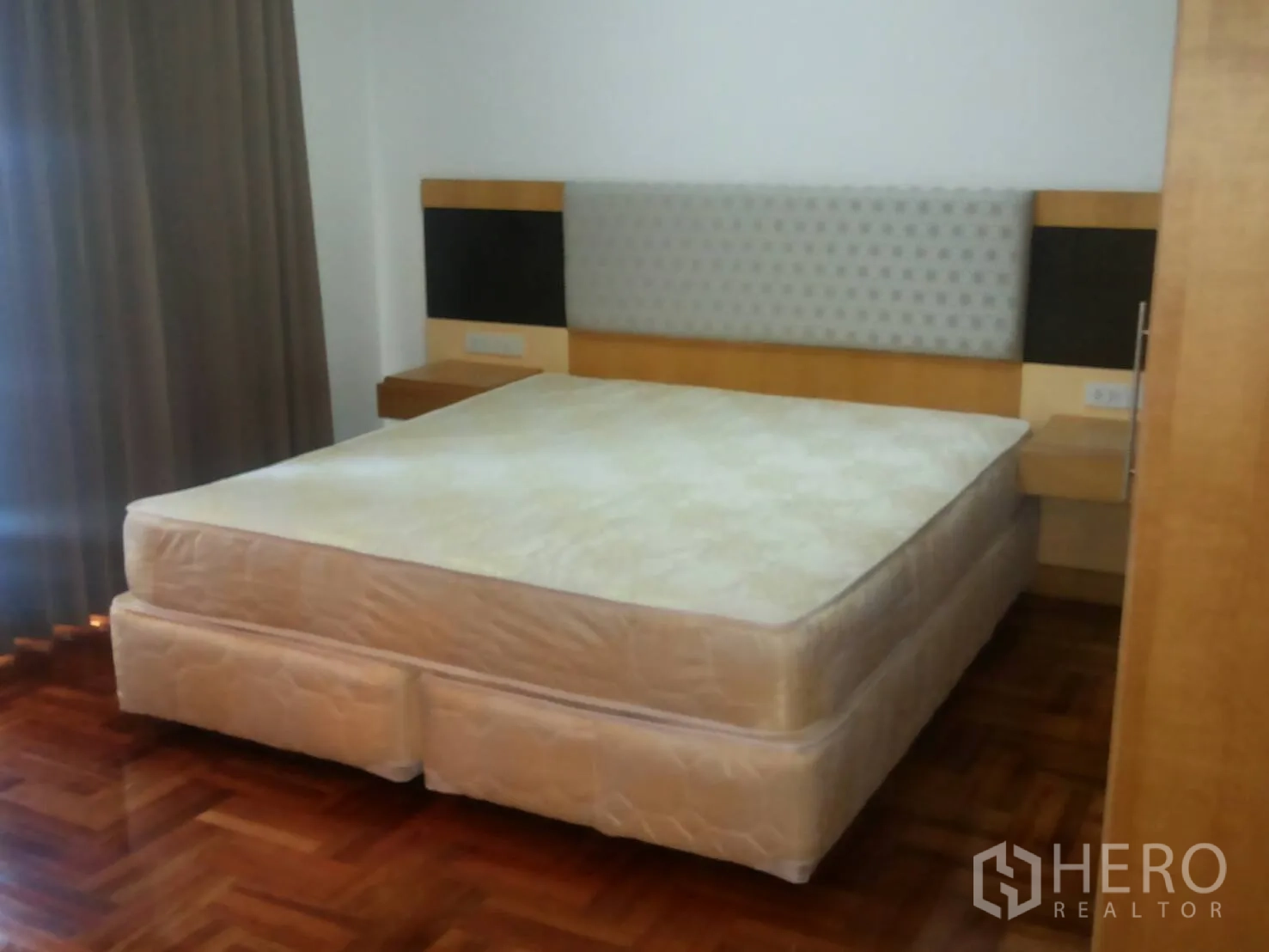 Apartment for rent in Khlong Toei, Bangkok - Second bedroom with upholstered headboard, bedside shelves, and parquet flooring.