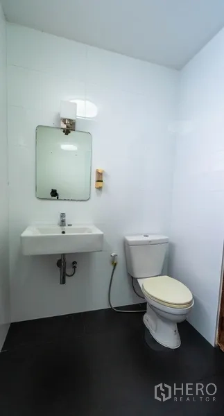 Townhouse for rent in Watthana, Bangkok - Compact bathroom with toilet, sink, and mirror.