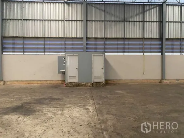 Warehouse for rent in Lat Krabang, Bangkok - Interior warehouse wall with utility cabinets, louvered ventilation panels and smooth concrete floor.