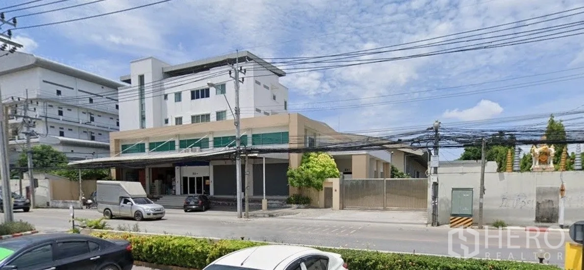Factory for rent in Bang Phli, Samut Prakan - Street view of a large factory complex with multi-storey office, loading canopy and gated entrance.