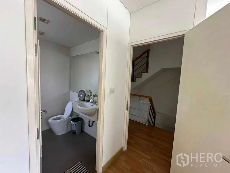 Home Office for rent in Chatuchak, Bangkok - Hallway with guest bathroom and a wooden staircase leading upstairs.