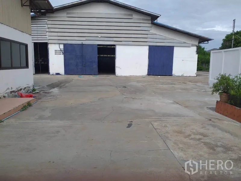 货栈 出租在Pak Kret, Nonthaburi - Pak Kret 仓库外观，蓝白色推拉门，前方大型混凝土装卸场。