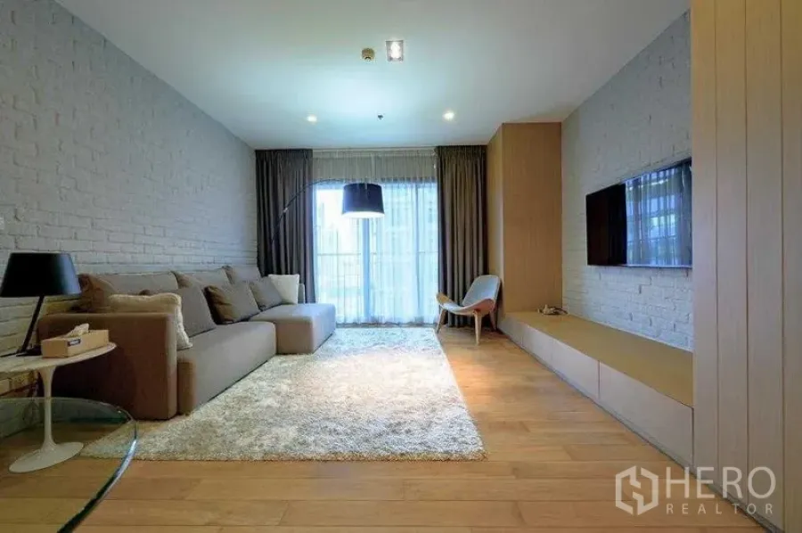 Condominium for rent in Watthana, Bangkok - Spacious living room with plush rug, sectional sofa and large window.
