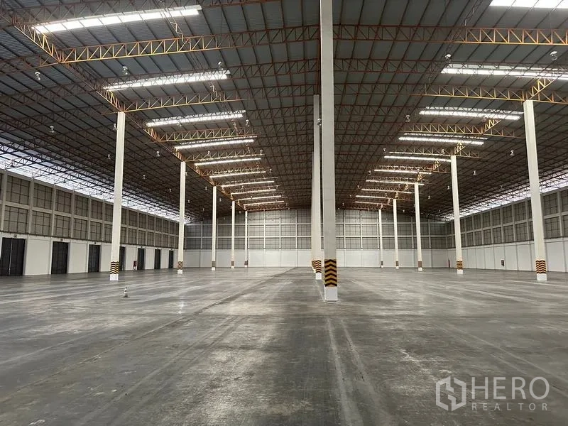 Warehouse for rent in Phra Nakhon Si Ayutthaya - Symmetrical view down central aisles of warehouse with illuminated roof panels.