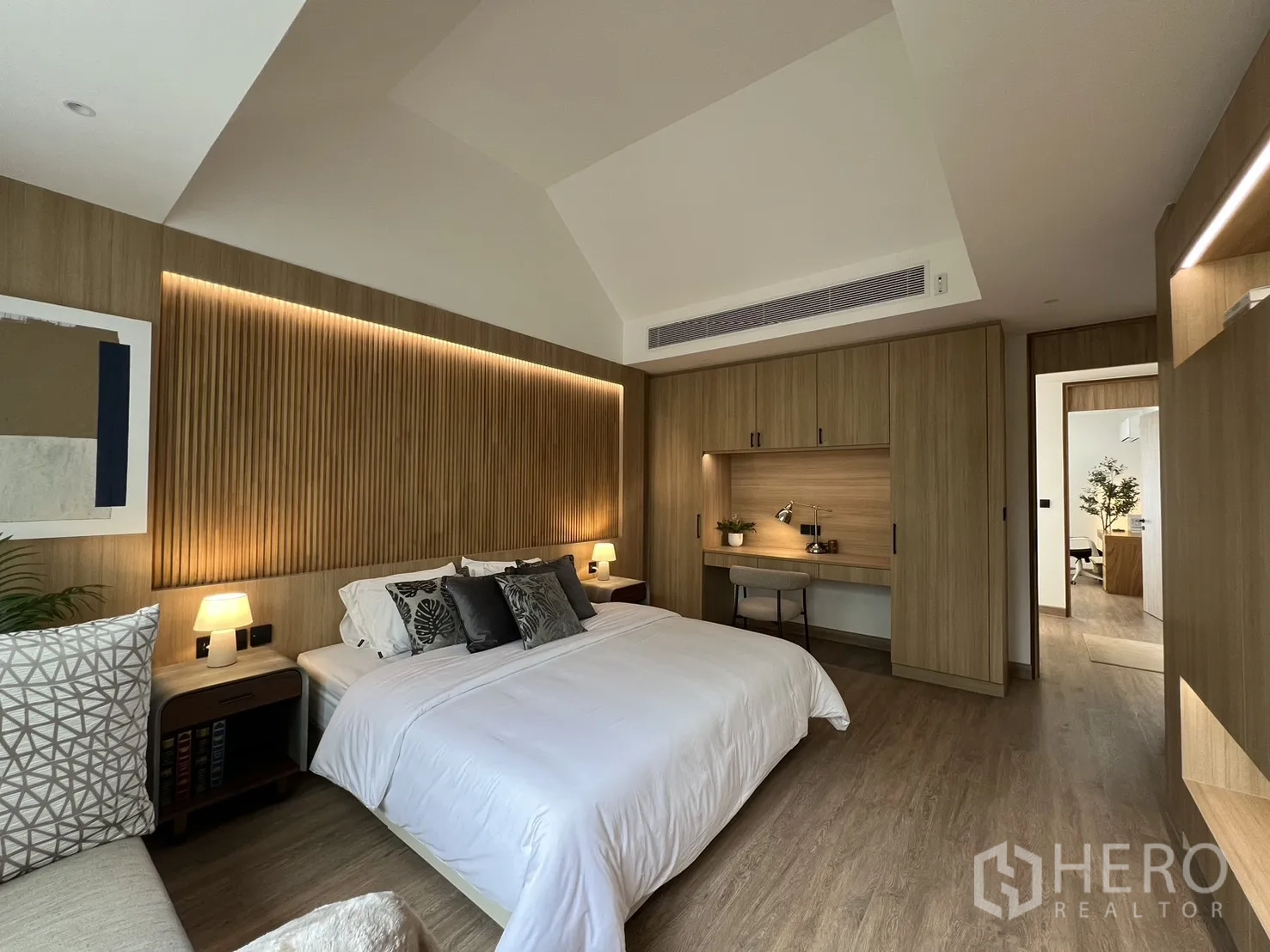 Townhouse for sale in Watthana, Bangkok - Primary suite with TV wall, shelving and window seat facing greenery.