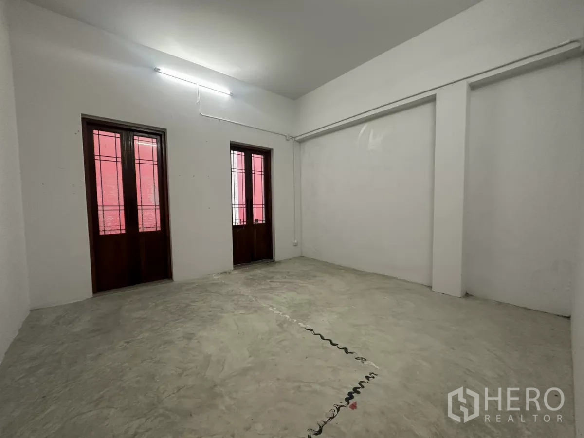 Home Office for rent in Pathum Wan, Bangkok - Room with two wooden-framed windows and concrete floor under fluorescent light.