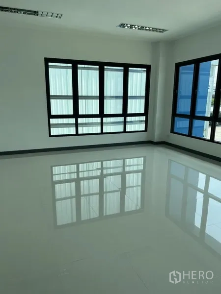 Factory for rent in Bang Sao Thong, Samut Prakan - Bright office room with glossy white tile floor and large black-framed windows.
