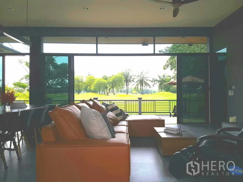 Detached House for rent or sale in Lam Luk Ka, Pathum Thani - Spacious lounge with sofa set and panoramic glass wall overlooking a green golf course.