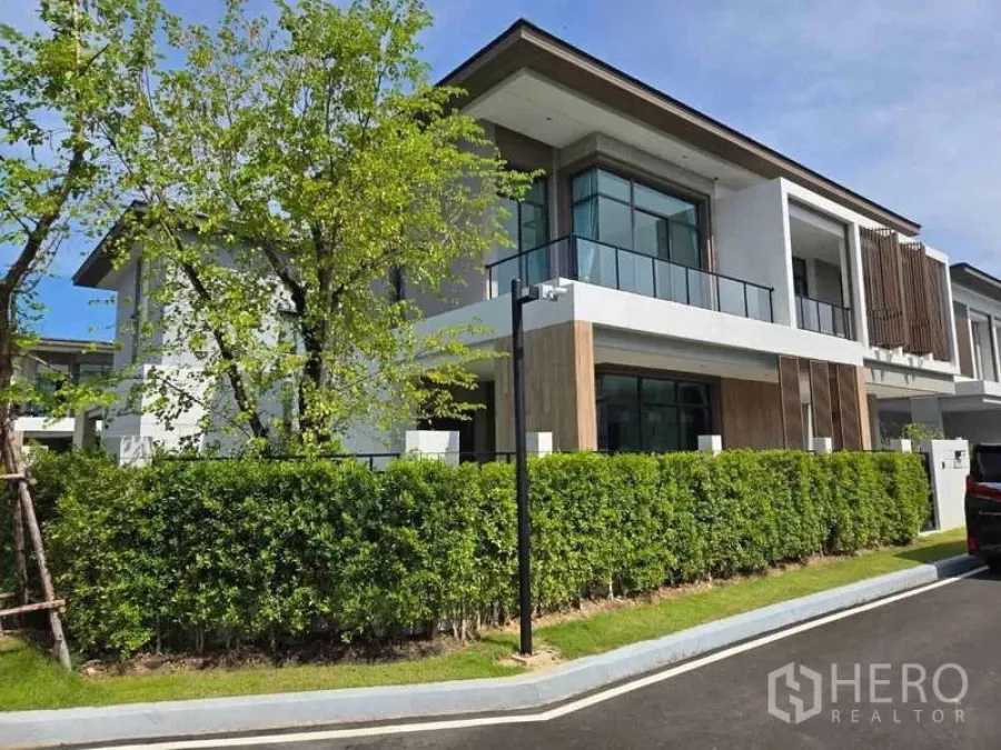 独立式住宅 出租在Bang Phli, Samut Prakan - 转角视角的现代独栋，玻璃阳台与绿篱。