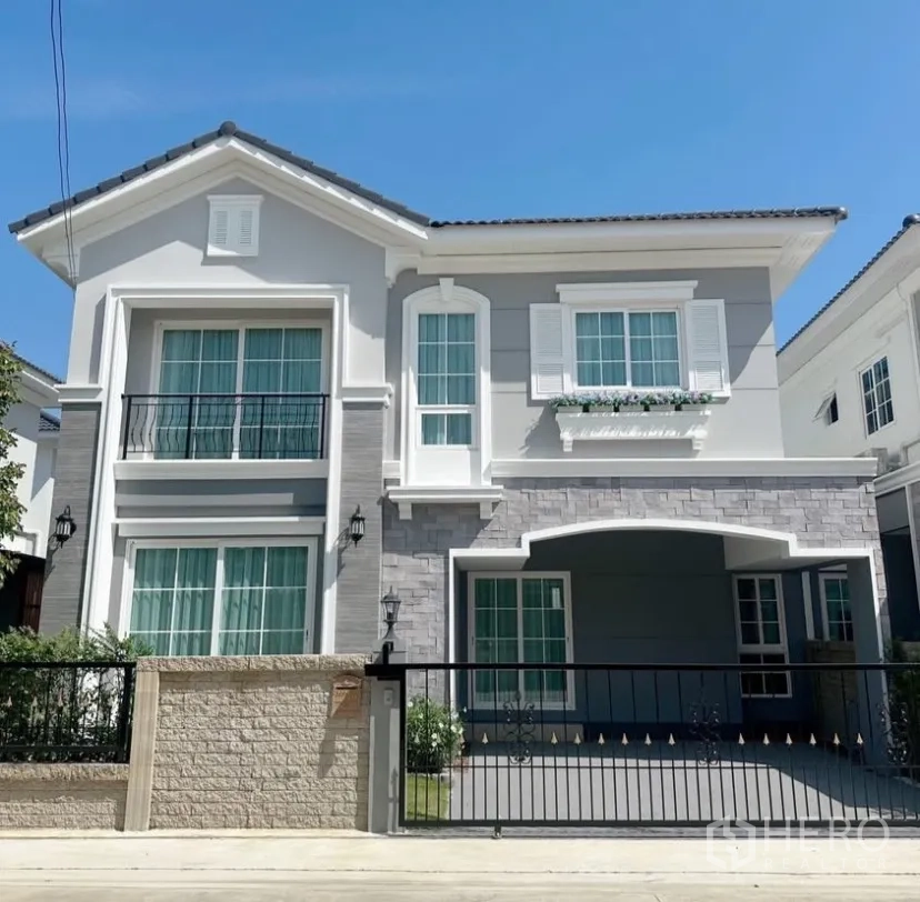 Detached House for rent in Mueang Samut Prakan, Samut Prakan - Two-storey modern detached house exterior with balconies, gate and covered parking.