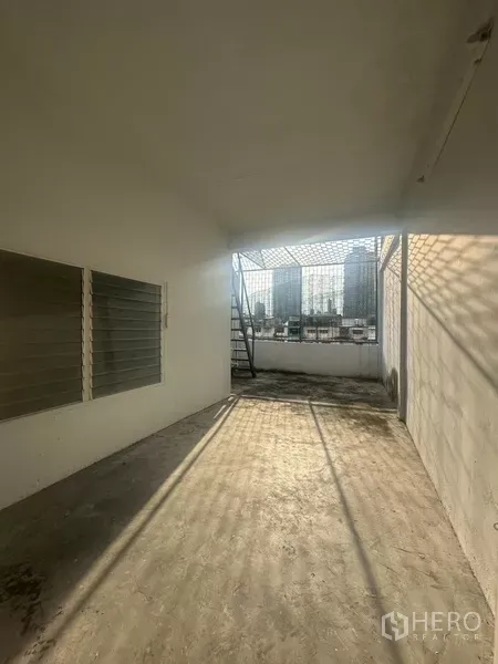 Shophouse for rent in Khlong Toei, Bangkok - Covered rear terrace with mesh roof and city skyline views, concrete floor.