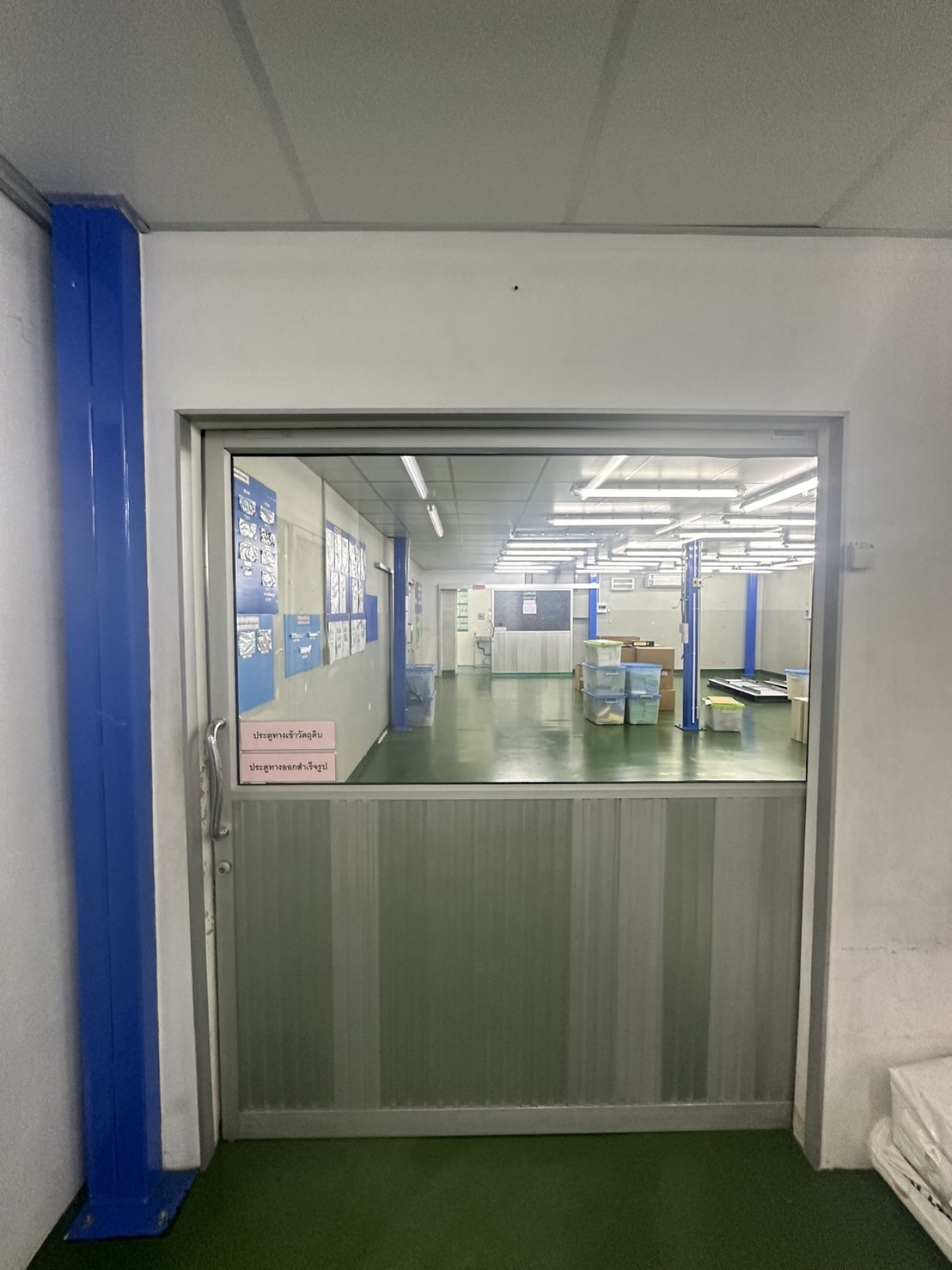 Warehouse for rent or sale in Lam Luk Ka, Pathum Thani - Sliding door entry to a clean production area with fluorescent lighting and epoxy flooring.