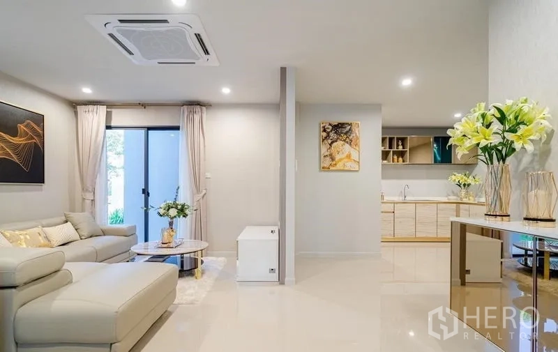 Detached House for sale in Lam Luk Ka, Pathum Thani - Bright open-plan living room with sofa and sliding door next to the kitchen.