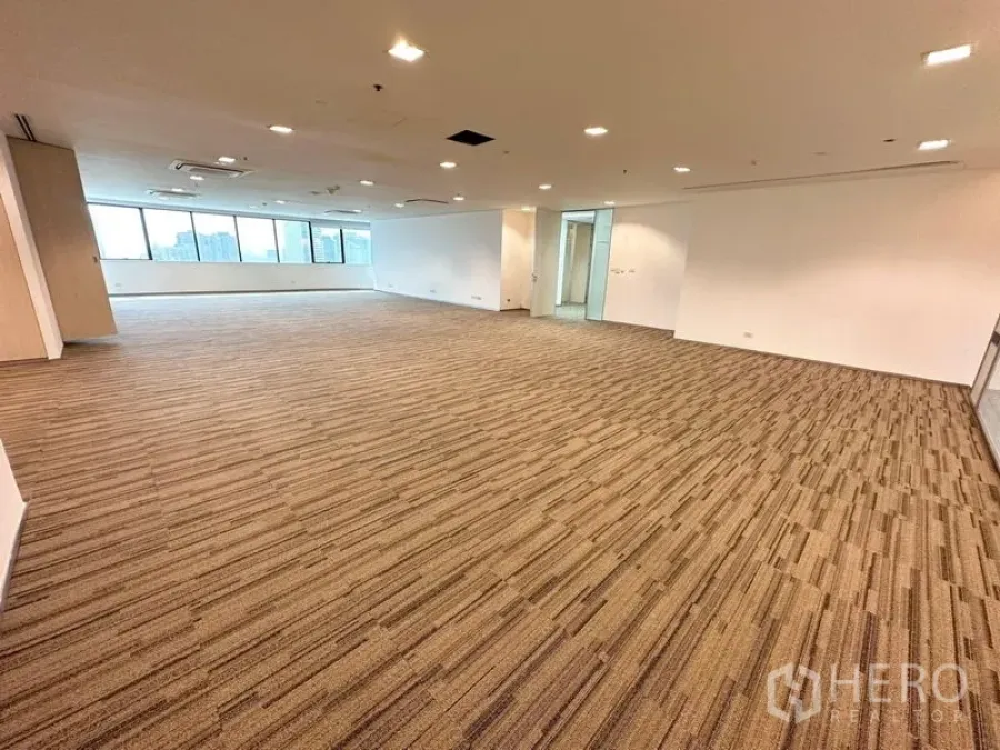 Office Space for rent in Watthana, Bangkok - Open office zone with curved wall of windows, suspended lights and neutral carpeting.
