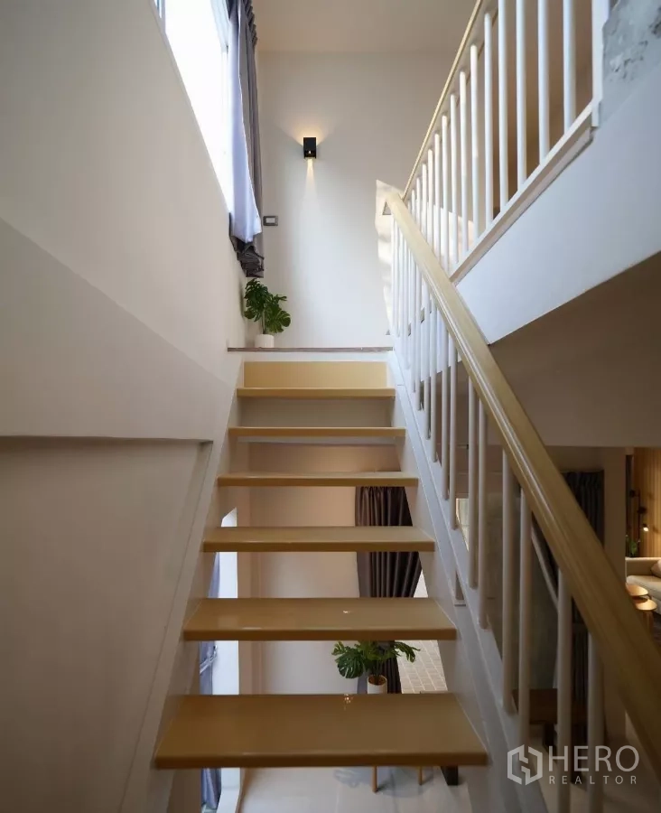Townhouse for rent or sale in Watthana, Bangkok - Open-riser wooden staircase with white railing and side window bringing in natural light.