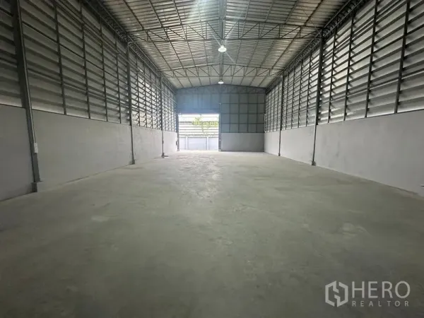 Warehouse for rent in Prawet, Bangkok - Clear-span warehouse looking toward the loading entry, bright LED lighting and ventilation panels along both sides.