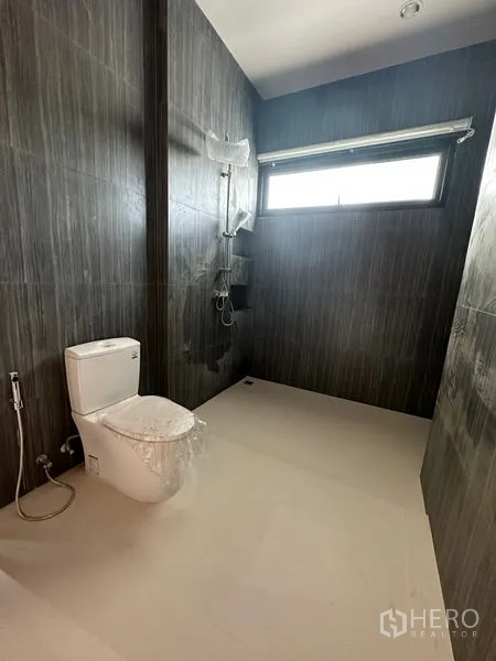 Detached House for rent in Watthana, Bangkok - Dark-tiled bathroom with walk-in shower, window, and modern sanitary ware.