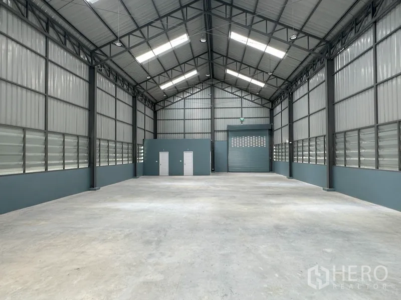 工厂 出租在Khlong Luang, Pathum Thani - 仓库内部朝向卷帘门与服务间，采光来自屋顶天窗。