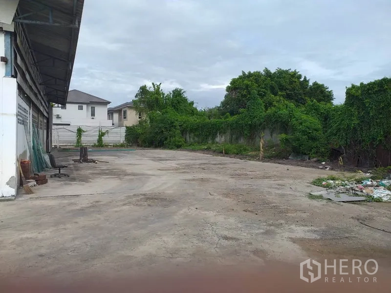 货栈 出租在Pak Kret, Nonthaburi - 仓库后侧硬化空地，围墙及周边绿化。