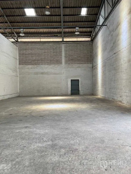 Warehouse for rent in Bang Phlat, Bangkok - High-ceiling warehouse interior with concrete floor and ventilation block wall in Bang Phlat, Bangkok.