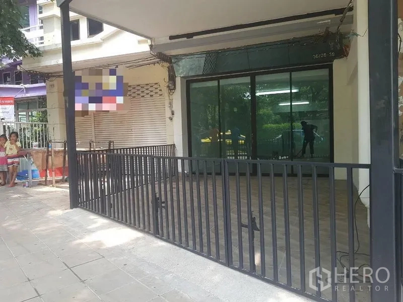 Shophouse for rent or sale in Lat Phrao, Bangkok - Covered front terrace with black metal fence and wide sliding glass shopfront.