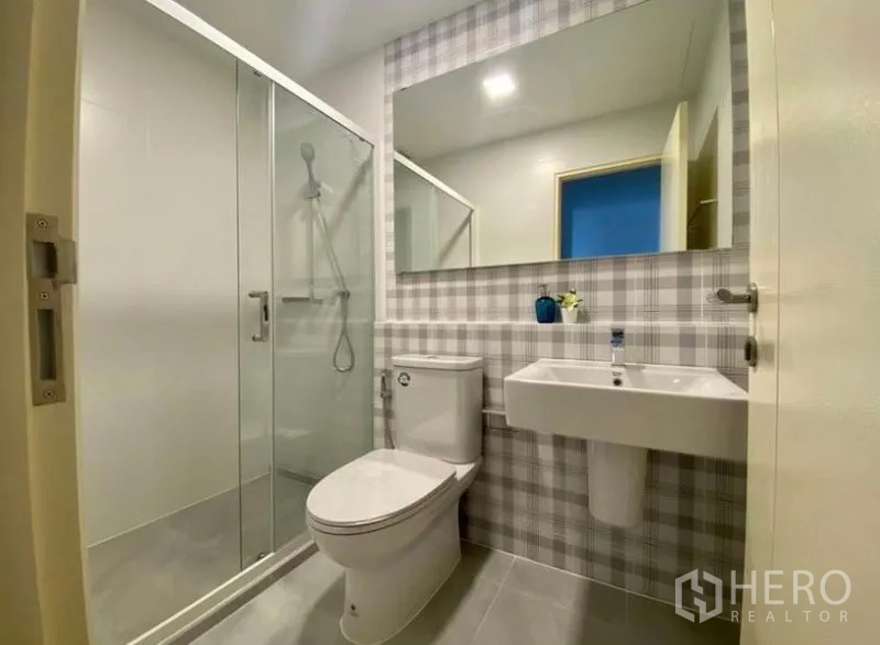 Townhouse for rent in Bang Phli, Samut Prakan - Contemporary bathroom with glass-enclosed shower, plaid accent tiles and white sanitaryware.