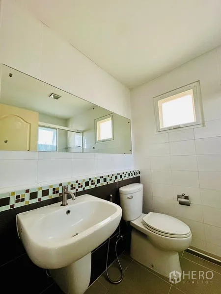 Detached House for sale in Prawet, Bangkok - Compact guest bathroom with wide mirror, sink and toilet.