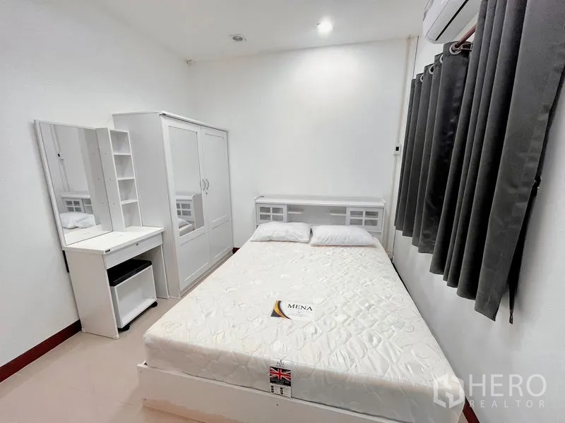 Townhouse for rent in Huai Khwang, Bangkok - Cozy guest bedroom with bed, wardrobe, vanity and blackout curtains.