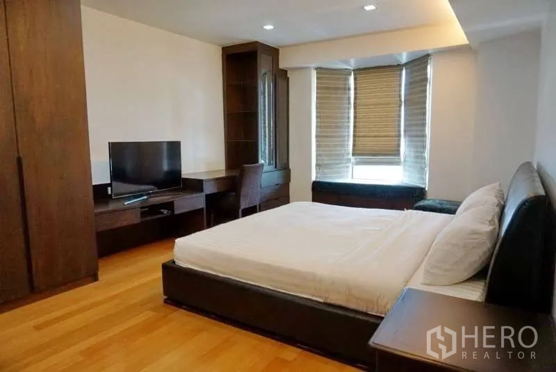 Condominium for rent in Watthana, Bangkok - Primary bedroom with king bed, built-in desk, TV and bay window seat.