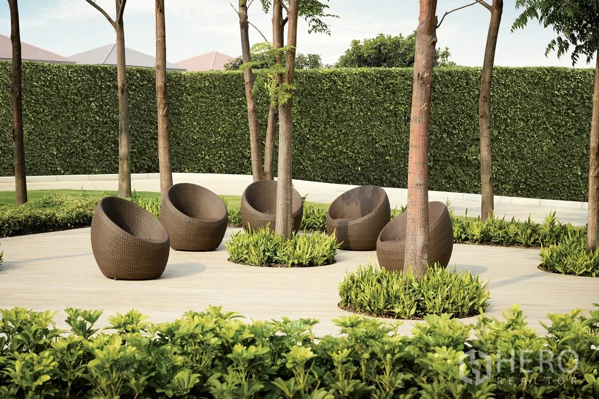 Detached House for rent or sale in Pathum Thani - Garden relaxation area with round wicker chairs beneath trees.