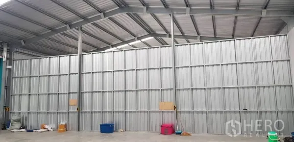 Warehouse for rent in Bang Yai, Nonthaburi - High-clearance warehouse interior showing steel truss roof and partition wall.