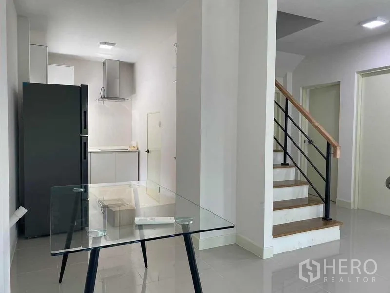 Detached House for rent in Khan Na Yao, Bangkok - Open dining and kitchen space with glass table next to stairway.