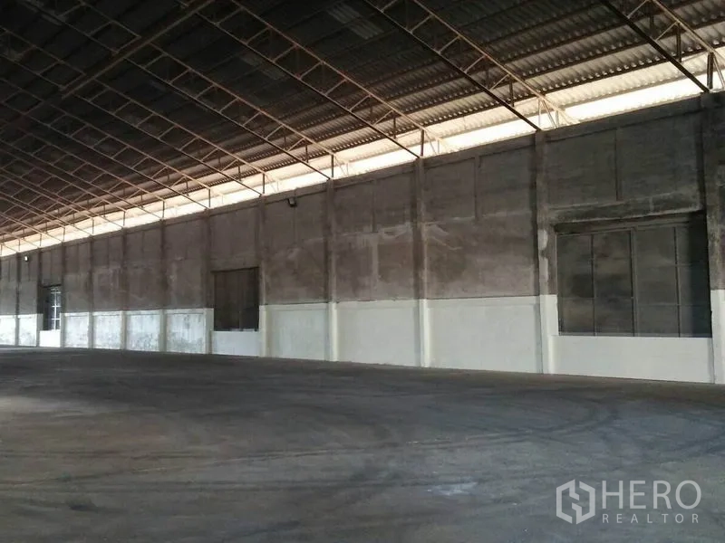 Warehouse for rent in Pathum Thani - Side wall of the warehouse with high eaves, concrete floor and large shutter openings along the perimeter.