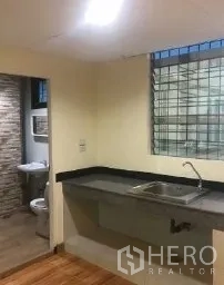 办公空间 出租在Bang Rak, Bangkok - 茶水间水槽与台面，旁边是瓷砖卫生间。